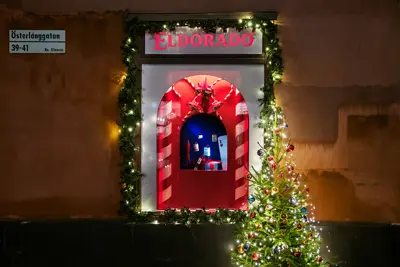 Julpyntat skyltfönster bredvid julgran med julkulor